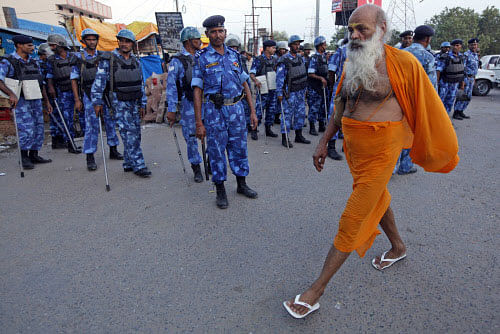 File photo of a holy man walks past security personnel standing guard in Ayodhya. AP