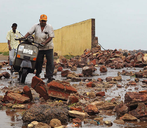 People walk among debris from a broken wall after it was damaged by a wave brought by Cyclone Phailin at a fishing harbour in Visakhapatnam district in the southern Indian state of Andhra Pradesh October 12, 2013. Rain and wind lashed India's east coast on Saturday, forcing more than 400,000 people to flee to storm shelters as one of the country's largest cyclones closed in, threatening to cut a wide swathe of devastation through farmland and fishing hamlets. Filling most of the Bay of Bengal, Cyclone Phailin was about 200 km (124 miles) offshore by noon on Saturday, satellite images showed, and was expected to hit land by nightfall. REUTERS