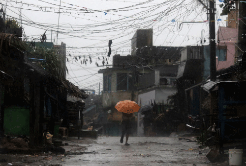 A man tries to cover himself with an umbrella during heavy rain brought by Cyclone Phailin as he moves towards a safer place at the village Donkuru in Srikakulam district in Andhra Pradesh. Reuters
