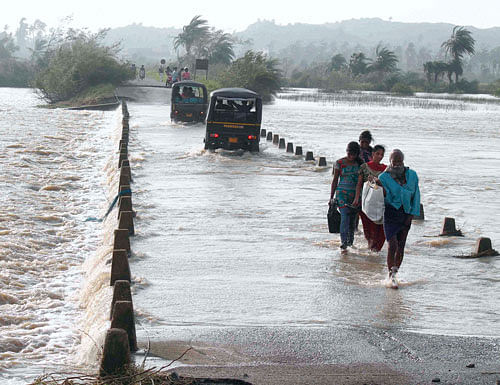 Villagers wade through flooded road after cyclone strike at Gopalpur village of Ganjam on Sunday. PTI Photo