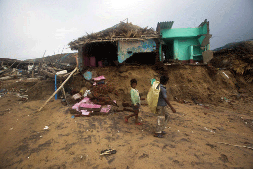 Boys walk past damaged houses belonging to fishermen after Cyclone Phailin hit Puri, Odisha October 14, 2013. A mass evacuation saved thousands of people from India's fiercest cyclone in 14 years, but aid workers warned a million would need help after their homes and livelihoods were destroyed. Cyclone Phailin was expected to dissipate within 36 hours, losing momentum on Sunday as it headed inland after making landfall from the Bay of Bengal, bringing winds of more than 200 kph (125 mph) that ripped apart tens of thousands of thatched huts, mangled power lines and tore down trees. REUTERS