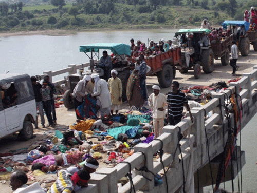 People walk past bodies of victims killed in a stampede on a bridge in Datia