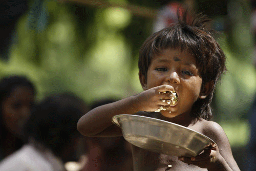 A homeless child eats rice on a roadside in Allahabad, India, Friday, July 5, 2013. The Indian government on Wednesday decided to come out with an ordinance to give two-third of the nation's population the right to 5 kilograms of food grains every month at a highly subsidized rate of 1-3 rupees per kilogram ($0.016- 0.05). If implemented, the country's food security program will be the largest in the world. AP photo
