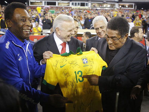Soccer greats Pele (L) of Brazil and Eusebio (R) of Portugal hold a signed Brazil jersey. Brazilian football legend Pele broke down and burst into tears Wednesday as he recalled his celebrated career during the launch of a book about him that weighs 15 kg and is worth $1,700. Reuters File Photo
