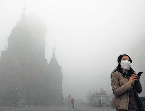 Alarming Situation: A woman wearing a mask checks her mobile phone during a smoggy day on the square in front of Harbin's landmark San Sophia church, in Heilongjiang province on Monday. REUTERS