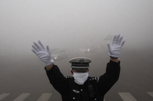 A traffic policeman signals to drivers during a smoggy day in Harbin, Heilongjiang province, October 21, 2013. The second day of heavy smog with a PM 2.5 index has forced the closure of schools and highways, exceeding 500 micrograms per cubic meter on Monday morning in downtown Harbin, according to Xinhua News Agency. REUTERS