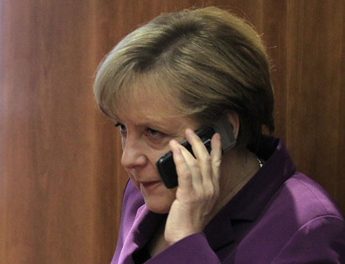 Germany's Chancellor Angela Merkel uses her mobile phone before a meeting at a European Union summit in Brussels in this December 9, 2011 file photo. The German government has obtained information that the United States may have monitored the mobile phone of Chancellor Angela Merkel and she called President Barack Obama on October 23, 2013 to demand an immediate clarification, her spokesman said. REUTERS