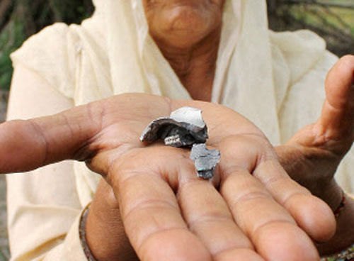 A woman displays part of a mortar shell, allegedly fired from Pakistan side at Pindi Charkhan village in Arnia sector of RS Pura on Thursday. PTI Photo