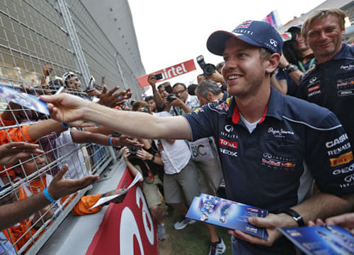 Red Bull Formula One driver Sebastian Vettel of Germany distributes autographed pictures of him to his fans at the Buddh International Circuit in Greater Noida on the outskirts of New Delhi October 24, 2013. The Indian F1 Grand Prix will take place from October 25-27. REUTERS