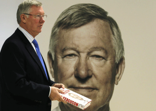 Former Manchester United manager Alex Ferguson poses with his new autobiography before a book signing at a supermarket in Manchester. Reuters