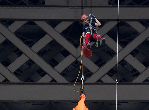 A fireman, top, speaks with a Greenpeace activist with a banner reading 'Free the Arctic 30', as he protests suspended from the second floor of the Eiffel Tower against Russia's detention of members of the environmental group, Paris, Saturday, Oct. 26, 2013. Russia's main investigative agency said Wednesday, Oct. 23, 2013 that it has dropped piracy charges against jailed Greenpeace activists and charged them instead with hooliganism, which could still mean years in prison. Banner reads: 'Militants in prison, climate in danger'. (AP Photo/Christophe Ena)