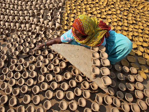 A woman puts out earthen lamps to dry in sun at her workshop ahead of the Hindu festival of Diwali in Chandigarh Reuters