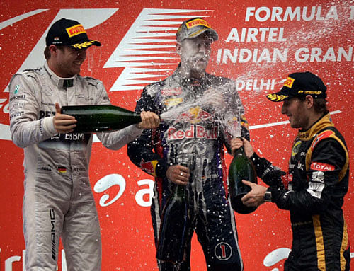 Red Bull driver Sebastian Vettel of Germany celebrates with Mercedes driver Nico Rosberg of Germany (L) who stood second and Lotus driver Romain Grosjean of France (R) who stood third, after winning the Indian Formula One Grand Prix at the Buddh International Circuit in Greater Noida on Sunday. PTI Photo