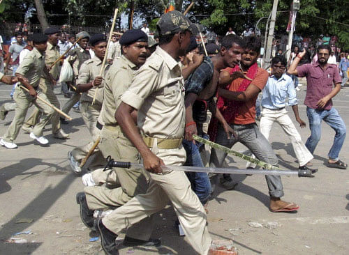 People thrash a man whom the police detain and take away for questioning after a bomb blast outside the venue of BJP's Hunkar rally in Patna on Sunday. PTI Photo