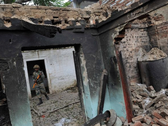 A security person walks in a burnt house at Kudba village in violence-hit Muzaffarnagar district. File PTI photo