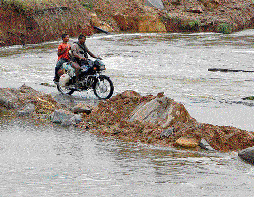 People ride a motorbike through a flood-damaged road on the outskirts of Hyderabad  in Andhra Pradesh on Saturday. AP