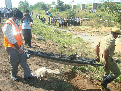 Rescue workers carry the remains of a passenger on Wednesday near Palem in Mahabubnagar.  DH photo.