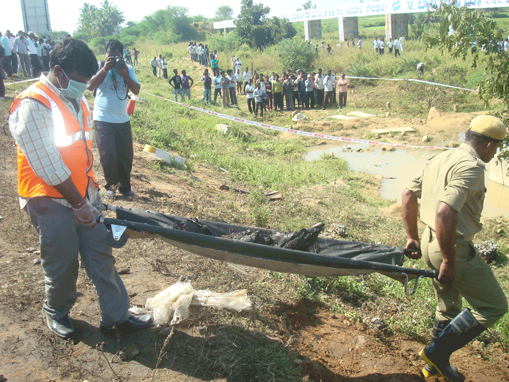 Rescue workers carry the remains of a passenger on Wednesday near Palem in Mahabubnagar.  DH photo.