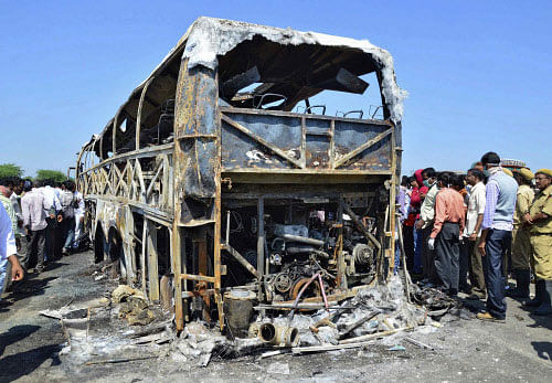 Aftermath: Onlookers stand next to a burnt bus after an accident at Mahabubnagar , Andhra Pradesh. Reuters