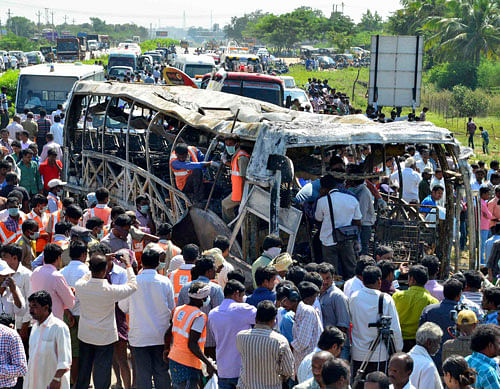 Onlookers stand next to a burnt bus after an accident at Mahabubnagar district in Andhra Pradesh. Reuters