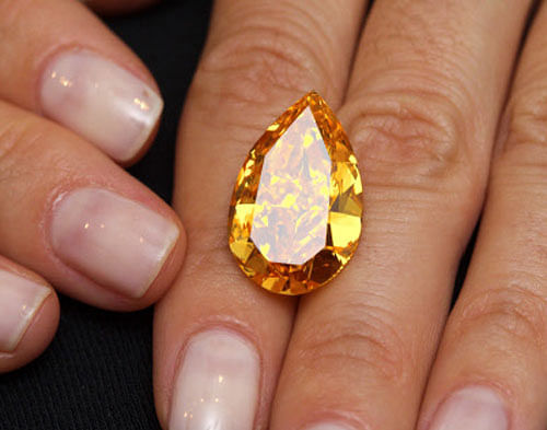 A Christie's member of staff displays 'The Orange', the world biggest orange diamond, which weighs 14.82 carats during an auction preview in Geneva November 1, 2013. The item is expected to sell around CHF 16,000,000 to 19,000,000 (US$ 17,000,000 to 20,000,000) when it goes into auction November 12, 2013 in Geneva. REUTERS