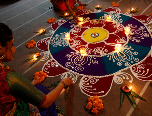 A woman arranges oil lamps and flowers around a Rangoli during the celebrations ahead of the Hindu festival of Diwali in Ahmedabad. Reuters