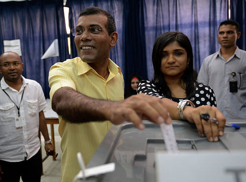 Maldivian Democratic Party (MDP) presidential candidate Mohamed Nasheed, who was ousted as president in 2012 (C), casts his vote at a polling station during the presidential elections in Male November 9, 2013. Voters streamed into polling booths in the Maldives to choose a new president on Saturday in an election that tests the democratic credentials of an Indian Ocean island state known more for its luxury resorts than its recent political turmoil. REUTERS