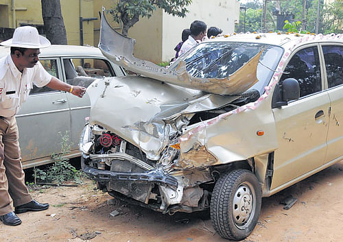 Fatal crash: A police constable looks at the car damaged in the accident, which killed Ashwathnarayan (inset) near the Brigade Road junction on Monday. DH Photo