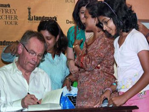Jeffrey Archer ,  while in India, autographs books for young readers of his works. PTI File photo