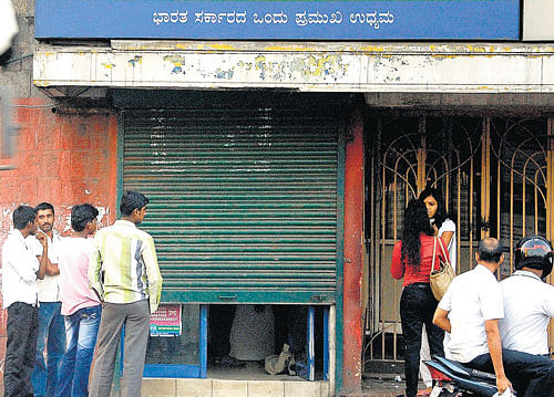 uneasy calm: People gather at the Corporation Bank ATM near BBMP head office, a day after a woman was assaulted by a robber inside the kiosk. KPN