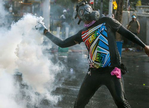 An anti-government protester throws back a teargas canister during clashes with police near government house in Bangkok December 1, 2013. Thousands of protesters launched a 'people's coup' on Thailand's government on Sunday, swarming multiple state agencies in violent clashes, taking control of a broadcaster and forcing the prime minister to flee a police compound. REUTERS