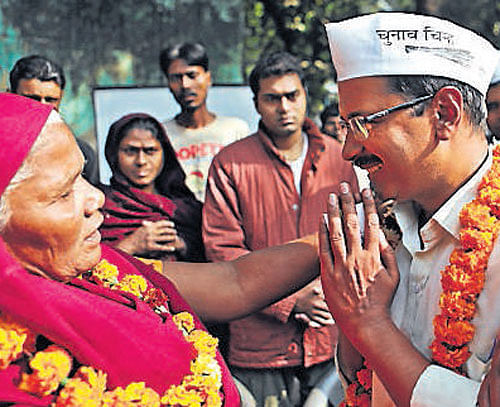 AAP chief Arvind Kejriwal seeks the blessings of a voter ahead of the Assembly elections in New Delhi on Monday. PTI
