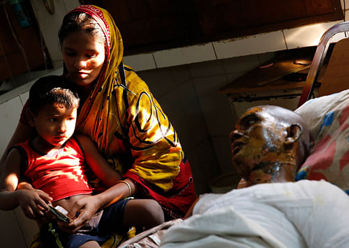 Aleya sits beside her husband Sabed Ali, an auto rickshaw driver, with her son Areef in Dhaka Medical College Hospital December 2, 2013. Ali sustained burns after protestors torched his auto rickshaw on Tuesday during a Bangladesh Nationalist Party (BNP)-led nationwide protest. At least five people were injured after protestors threw crude bombs, vandalized and torched vehicles in different parts of the city on Monday, local media reported. REUTERS