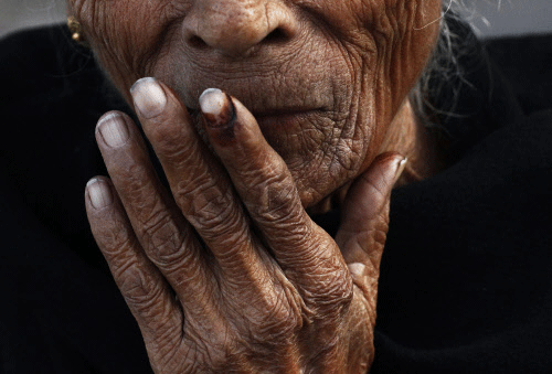 An elderly woman places her ink-marked finger on her lips after casting her vote outside a polling booth during the state assembly election in Delhi December 4, 2013. REUTERS