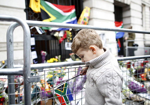 A South African boy, Grant, age three, looks at flowers laid in memory of Nelson Mandela outside the South African High Commission in central London December 7, 2013. Reuters