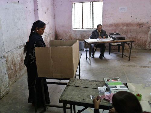 A woman (L) casts her vote inside a polling booth during the state assembly election in Delhi December 4, 2013. REUTERS