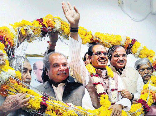 BJP leader and Madhya Pradesh's incumbent Chief Minister Shivraj Singh Chauhan waves to supporters as he is garlanded with other leaders while celebrating the party's victory in the state Assembly elections in Bhopal on Sunday. AP