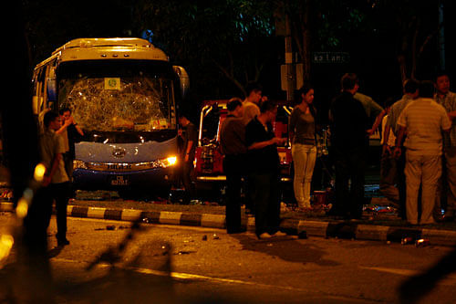 Officials stand around a bus with a smashed windshield following a riot in Singapore's Little India district. Reuters Image