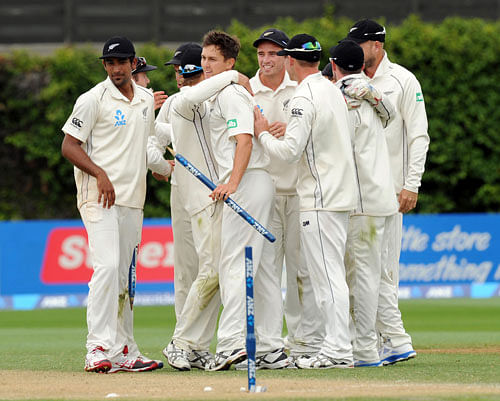 New Zealand's Trent Boult, center, is congratulated by his teammates after taking ten wickets against the West Indies on the third day of the second international cricket match at the Basin Reserve in Wellington, New Zealand, Friday, Dec. 13, 2013.AP Photo
