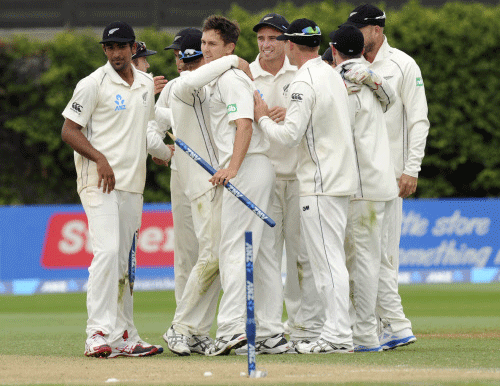 New Zealand's Trent Boult, center, is congratulated by his teammates after taking ten wickets against the West Indies on the third day of the second international cricket match at the Basin Reserve in Wellington, New Zealand, Friday, Dec. 13, 2013.(AP Photo