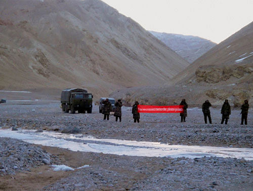 FILE- In this May 5, 2013 file photo, Chinese troop hold a banner which reads, 'You've crossed the border, please go back,' in Ladakh, India. AP Photo