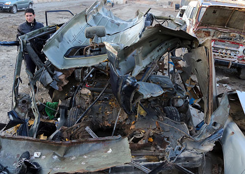 An Iraqi man inspects a bus damaged in a car bomb attack in Baghdad, Iraq, Monday, Dec. 16, 2013.  AP