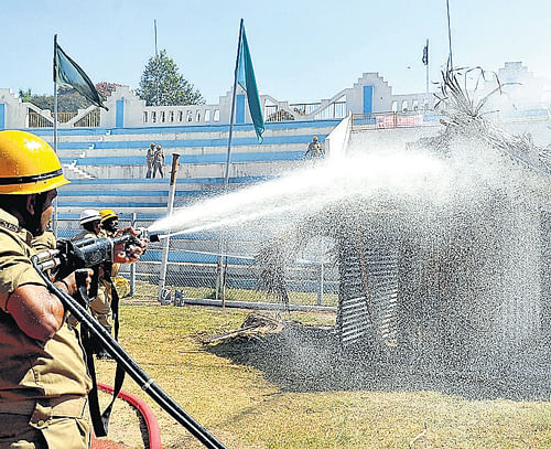 Testing preparedness: A firefighter puts out blaze during a mock drill organised as part of the National Disaster Reduction Day at Kanteerava Stadium in the City on Monday. dh photo