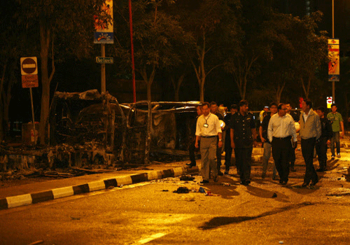 Singapore's Deputy Prime Minister Teo Chee Hean (front R) and Minister in Prime Minister's Office S Iswaran (front 2nd R) look at the site of two burnt vehicles following a riot in Singapore's Little India district, December 9, 2013. Local media said a mob of about 400 set fire to an ambulance and police cars during the riot on Sunday, which started after a bus knocked down a pedestrian. REUTERS