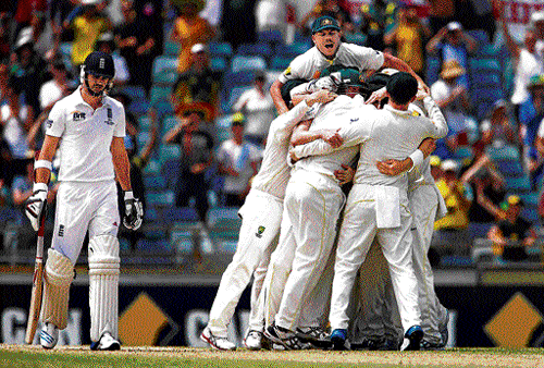 down and out: Australian players celebrate winning the Ashes after James Anderson (left) is dismissed by Mitchell Johnson on the fifth day of the third Test at the WACA on Tuesday. Australia thus took an unassailable 3-0 lead in the five-match series. reuters