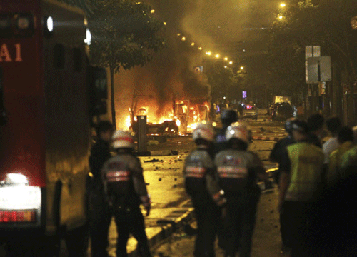 Riot policemen watch burning vehicles during a riot in Singapore's Little India district, late December 8, 2013. A crowd set fire to vehicles and clashed with police in the Indian district of Singapore late on Sunday, in a rare outbreak of rioting in the city state. Television footage showed a crowd of people smashing the windscreen of a bus, and at least three police cars being flipped over. The Singapore Police Force said the riot started after a fatal traffic accident in the Little India area. REUTERS