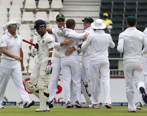 India's batsman Ajinkya Rahane, second from left, walks back to the pavilion as South Africa's bowler Vernon Philander, center, celebrates his dismissal with teammates during the second day of their cricket test match at Wanderers stadium in Johannesburg, South Africa, Thursday, Dec. 19, 2013. AP Photo