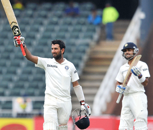 India's batsman Cheteshwar Pujara raises his bat to celebrate his hundred century during the third day of their cricket test match against South Africa in Johannesburg, December 20,2013. REUTERS