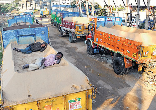 no work: Workers rest on lorries at the Baiyappanahalli sand lorry stand in Bangalore on Sunday. Dh Photo