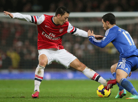 Arsenal's Mesut Ozil, left attempts to block Chelsea's Eden Hazard during their English Premier League soccer match between Arsenal and Chelsea at the Emirates stadium in London, Monday, Dec. 23, 2013. AP